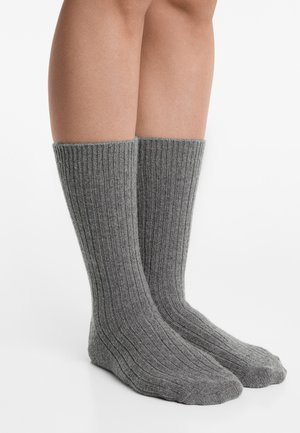 Grijze geribbelde sokken van zacht materiaal met een middenkuitlengte, voorzien van een gestructureerd patroon en versterkte tenen en hielen.