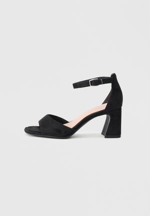 Black suede ankle strap sandal with a wide toe band, open toe, and a chunky heel. Features a silver buckle for adjustable fit.