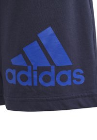 Navy cotton shorts featuring a large blue Adidas logo and three blue stripes design. The fabric has a smooth texture with a relaxed fit.