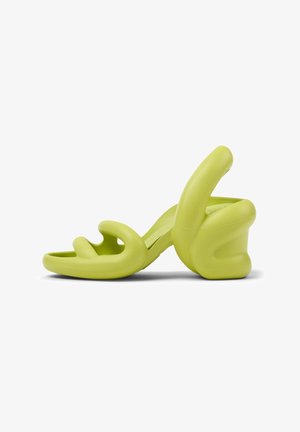 Green high-heeled sandal made of smooth polyurethane. Unique, curved design with cut-out sections and a chunky heel. Soft texture.