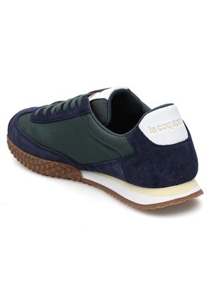 Baskets bleu marine et vert foncé avec semelle texturée marron, languette de talon blanche avec le logo "le coq sport" et design à lacets.
