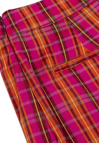 Heldere geruite stofshorts met kleuren zoals magenta, oranje en geel. Het materiaal is lichtgewicht met een gladde textuur en gestikte zakken.