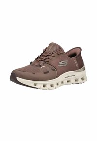 Baskets de sport marron en mesh avec semelle blanche, fermeture à lacets à l'avant et trous de ventilation, avec un logo argenté "S" sur le côté.