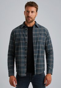 Flanellen shirt in marineblauw met een wit en lichtblauw ruitpatroon, met knoopsluiting aan de voorkant, lange mouwen en een zwart T-shirt met ronde hals eronder.