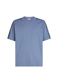 Camiseta corta de manga azul hecha de algodón, con cuello redondo, paneles en los hombros de un gris oscuro en contraste y un sutil logotipo en la manga.