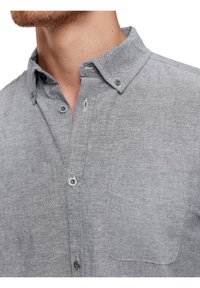 Szara bawełniana koszula z kołnierzykiem zapinanym na guziki, z przodu z listwą i kieszonką na lewej piersi. Posiada gładką teksturę i subtelny melanżowy wzór.