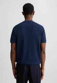 Mørkeblå kortærmet t-shirt lavet af blødt stof med rund hals, der har en afslappet pasform og sømløst skulderdesign.