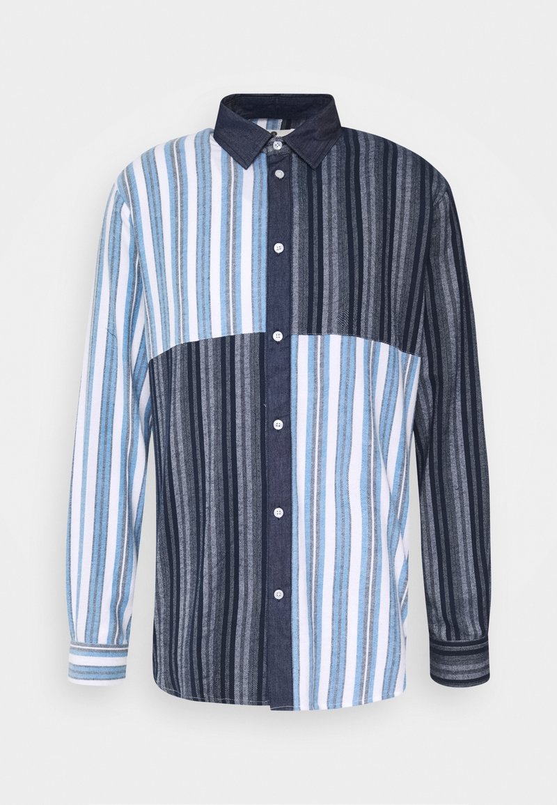 Chemise à manches longues boutonnée avec des rayures verticales bleues, blanches et noires en motif patchwork et un col foncé.