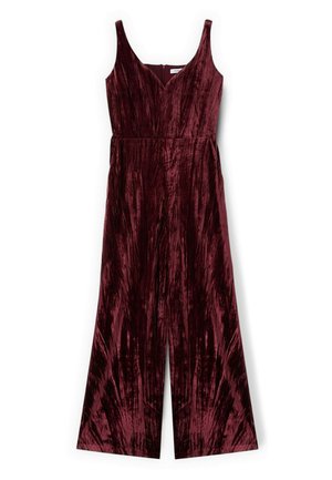 Bordeaux fluwelen jumpsuit met wijde benen, diepe V-hals en schouderbanden. Verticale textuurpatronen lopen door de stof. Verborgen ritssluiting aan de achterkant.