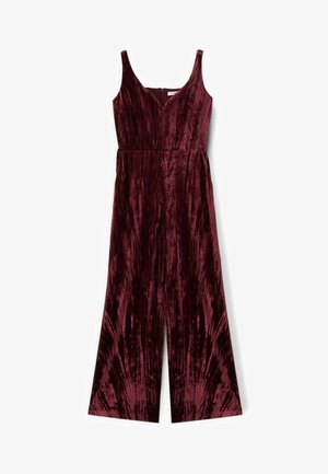 Bordeaux fluwelen jumpsuit met wijde benen, diepe V-hals en schouderbanden. Verticale textuurpatronen lopen door de stof. Verborgen ritssluiting aan de achterkant.