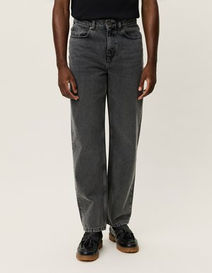 Svarta vida jeans i denim, med hög midja, kontrasterande sömmar och framfickor. Kombinerade med svarta skor.