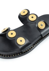 Sandalo in pelle nera con accenti circolari dorati con centri neri, suola piatta e borchie decorative dorate lungo il bordo.