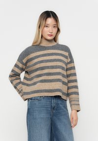 Stripet genser laget av mykt materiale, med grå og beige horisontale linjer, høy hals og en avslappet passform med ribbestrikket nederkant.