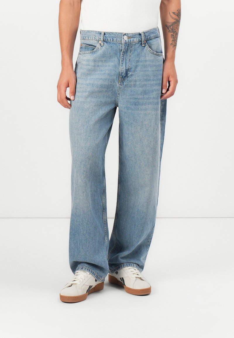 Svetlo modri široki jeansi iz denima, ki imajo klasičen dizajn s petimi žepi, bled nakit in kovinsko zaklepanje.
