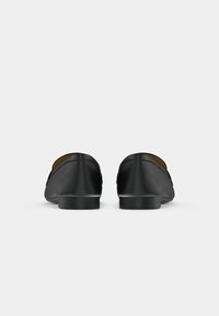 Black leather loafers with a smooth texture, rounded toe design, low flat heel, and a subtle trim detail along the edges.