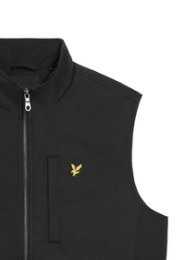Schwarzes ärmelloses Oberteil aus glattem Stoff, mit einem Frontreißverschluss und einer Brusttasche. Auffälliges gelbes Logo auf der linken Seite.