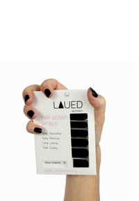 Zwarte nagellak strips gepresenteerd in een hand. De verpakking heeft een witte achtergrond met roze tekst en noemt de belangrijkste kenmerken.