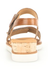 Brown leather sandal with cork-textured heel. Features multiple straps and a cushioned footbed on a white rubber sole.