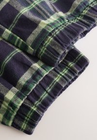 Tessuto di flanella a quadri in blu navy e verde con linee bianche a contrasto; presenta una trama morbida e polsini elastici.