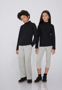 Schwarze langärmlige Oberteile mit hohen Kragen kombiniert mit grauen Sweatpants und knöchellangen Leggings; strukturierte Stoffe, lässige Passform, geeignet für Kinder.