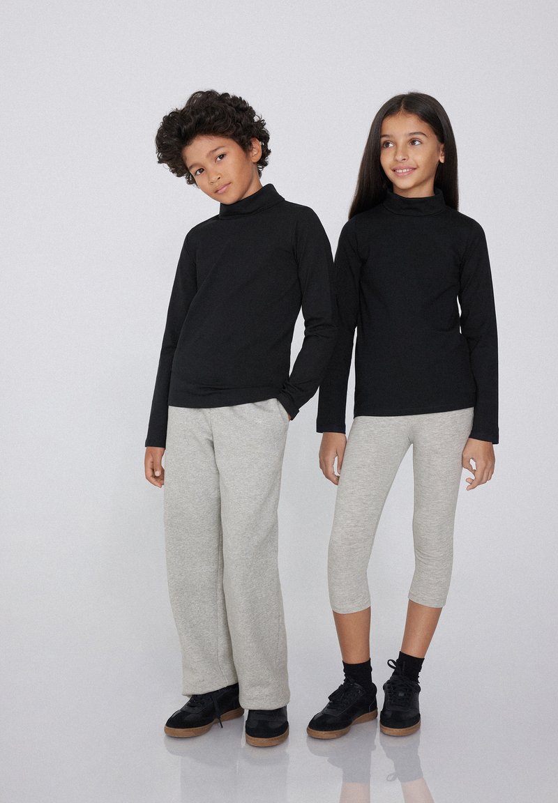 Schwarze langärmlige Oberteile mit hohen Kragen kombiniert mit grauen Sweatpants und knöchellangen Leggings; strukturierte Stoffe, lässige Passform, geeignet für Kinder.