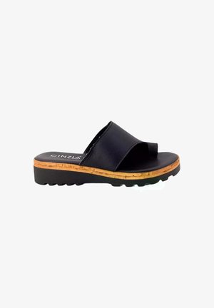 Sandal in pelle nera con una larga cinghia, accentuata da un dettaglio in sughero alla base e suola in gomma testurizzata. Design semplice con profilo piatto.