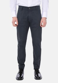 Chinos grigio scuro con taglio dritto, realizzati in tessuto liscio. Presentano una chiusura a bottone e frontale piatto. Abbinati a scarpe lucide nere.