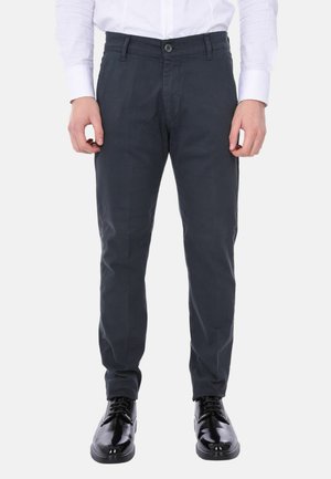 Chinos grigio scuro con taglio dritto, realizzati in tessuto liscio. Presentano una chiusura a bottone e frontale piatto. Abbinati a scarpe lucide nere.