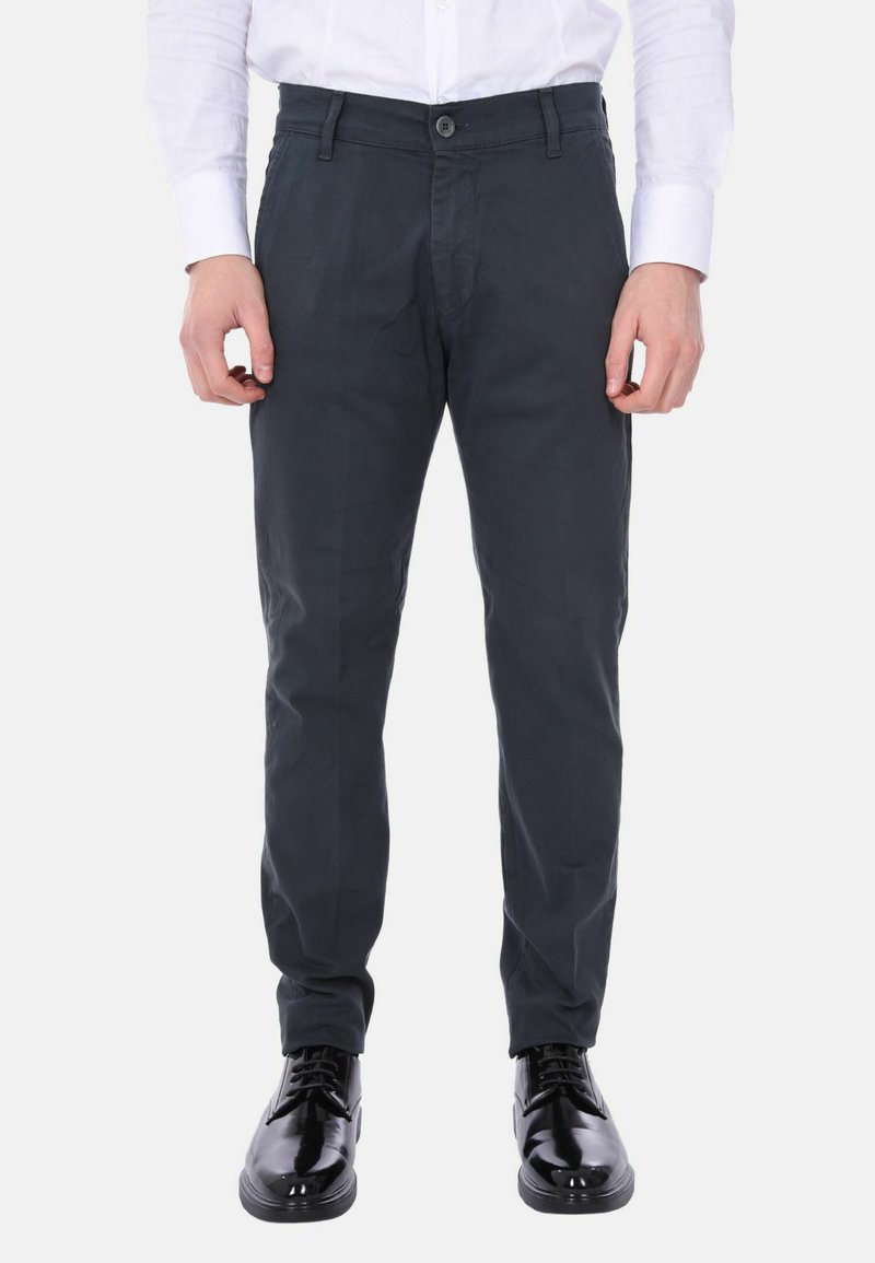 Chinos grigio scuro con taglio dritto, realizzati in tessuto liscio. Presentano una chiusura a bottone e frontale piatto. Abbinati a scarpe lucide nere.