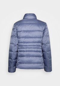 Blå puffjakke har en boxy form med horisontalt quiltede sektioner, en stående krave og en glat, skinnende stofstruktur.