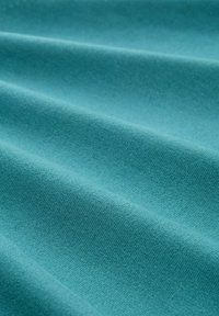 Türkisfarbenes Gewebe mit glatter Textur, das sanfte Falten und subtile Dehnung aufweist. Die Oberfläche zeigt ein feines, gleichmäßiges Webmuster.