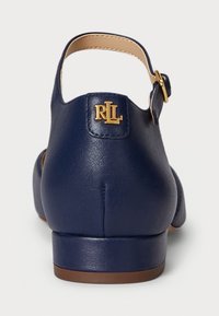 Ναυτικό μπλε δερμάτινο παπούτσι με λουράκι στον αστράγαλο, στρογγυλή μύτη και ψηλό τακούνι. Διαθέτει χρυσό λογότυπο στην φτέρνα. Λειαία υφή.