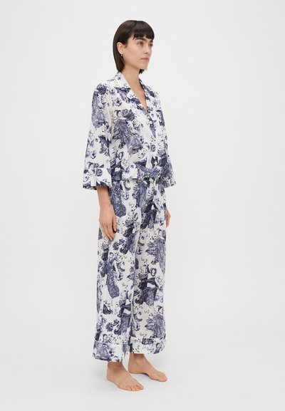 Pajama set s cvjetnim uzorkom u bijeloj i tamnoplavoj boji, s kragnom i rukavima do tri četvrtine, te širokim hlačama s remenom.