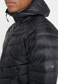 Černá péřová bunda s horizontálním prošíváním, vysokým límcem, kapsami na zip a logem na rukávu. Hladká, lesklá textura.