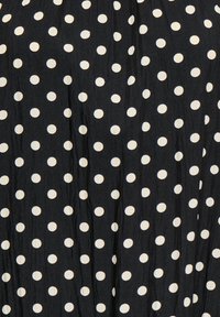 Tissu noir avec de petits pois blancs espacés uniformément, disposés en motif quadrillé.