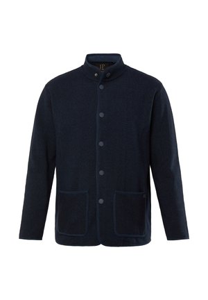 Chaqueta azul marino con un cuello alto, cierre de botones, dos bolsillos frontales y tejido texturizado. Ribete de contraste a lo largo de los bordes.