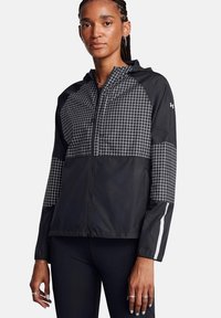 Giacca leggera nera con un motivo a griglia sulla parte superiore anteriore e sulle maniche, dotata di chiusura a zip e dettagli riflettenti bianchi.