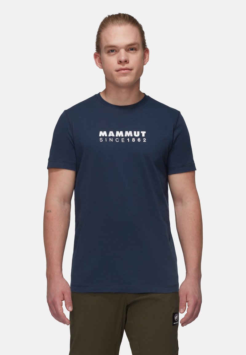 Mørkeblå kortærmet t-shirt lavet af bomuld, med et hvidt "MAMMUT SINCE 1862" logo på forsiden. Rund halsudskæring, tætsiddende design.
