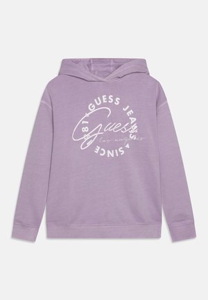 Sweat à capuche lilas avec un logo circulaire blanc à l'avant indiquant "Guess Jeans Since 1981 Los Angeles" et manches longues.