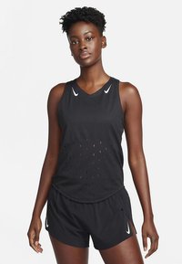 Schwarzes Sporttop mit perforiertem Design, Rundhalsausschnitt und weißen Nike-Logos; kombiniert mit passenden schwarzen Shorts mit Seitenschlitzen.