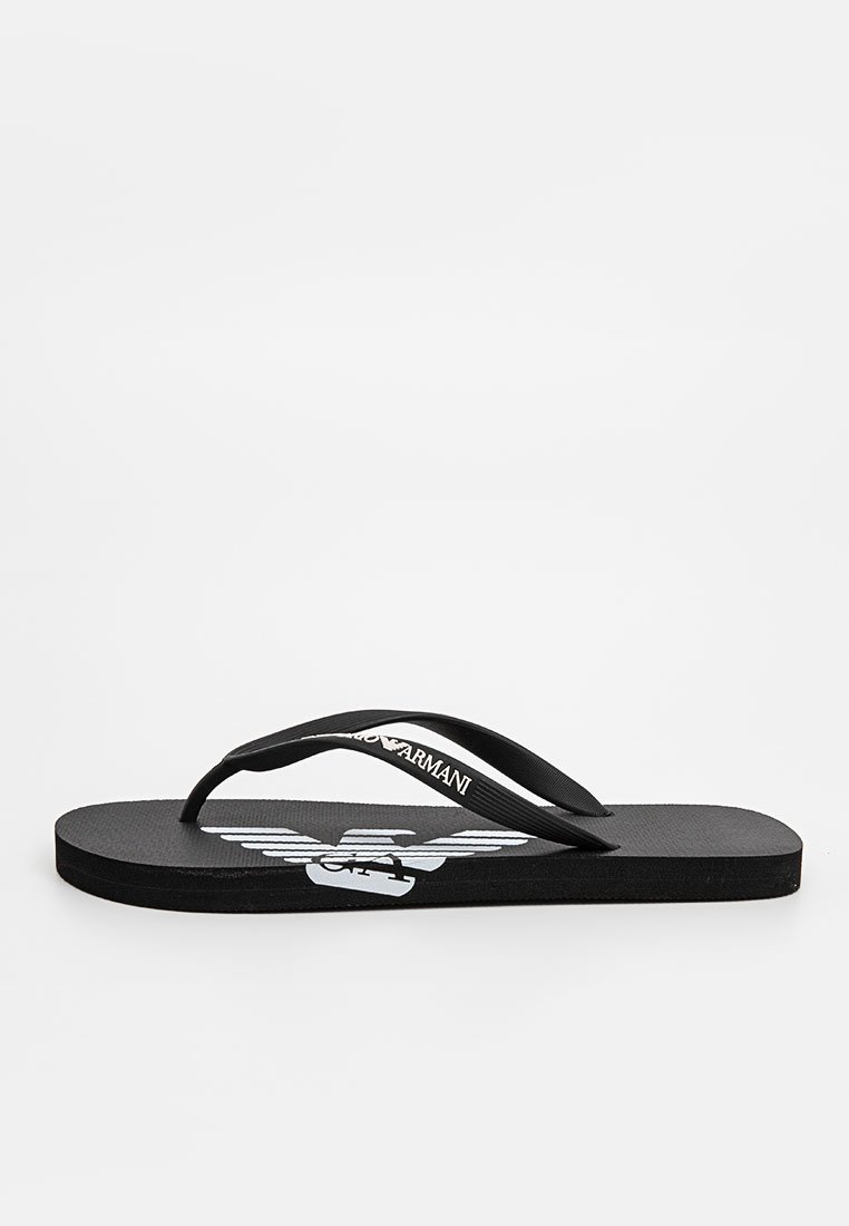 Schwarze Flip-Flops mit strukturierten Sohlen und zwei dünnen Riemen. Auf der Fußbett befindet sich ein weißes Logo-Design und Branding auf dem Riemen.
