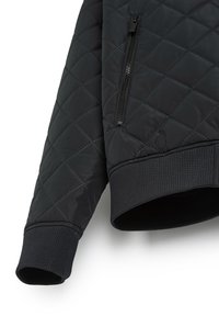 Pikowana czarna kurtka z zamykanymi na zamek kieszeniami, prążkowanymi mankietami i gładką, lekko błyszczącą teksturą. Charakteryzuje się nowoczesnym, skośnym wzornictwem.