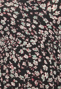 Tecido floral preto com pequenas flores verde menta e vermelhas, apresentando um design texturizado e franzido ao longo da costura.