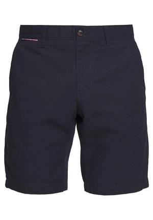 Short en coton bleu marine foncé avec fermeture par bouton, passants pour ceinture et un petit détail en tissu tricolore près de la taille côté gauche.