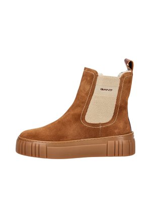 Brown suede ankle boot with a textured beige elastic side panel, featuring a thick rubber sole with vertical grooves and a pull tab.