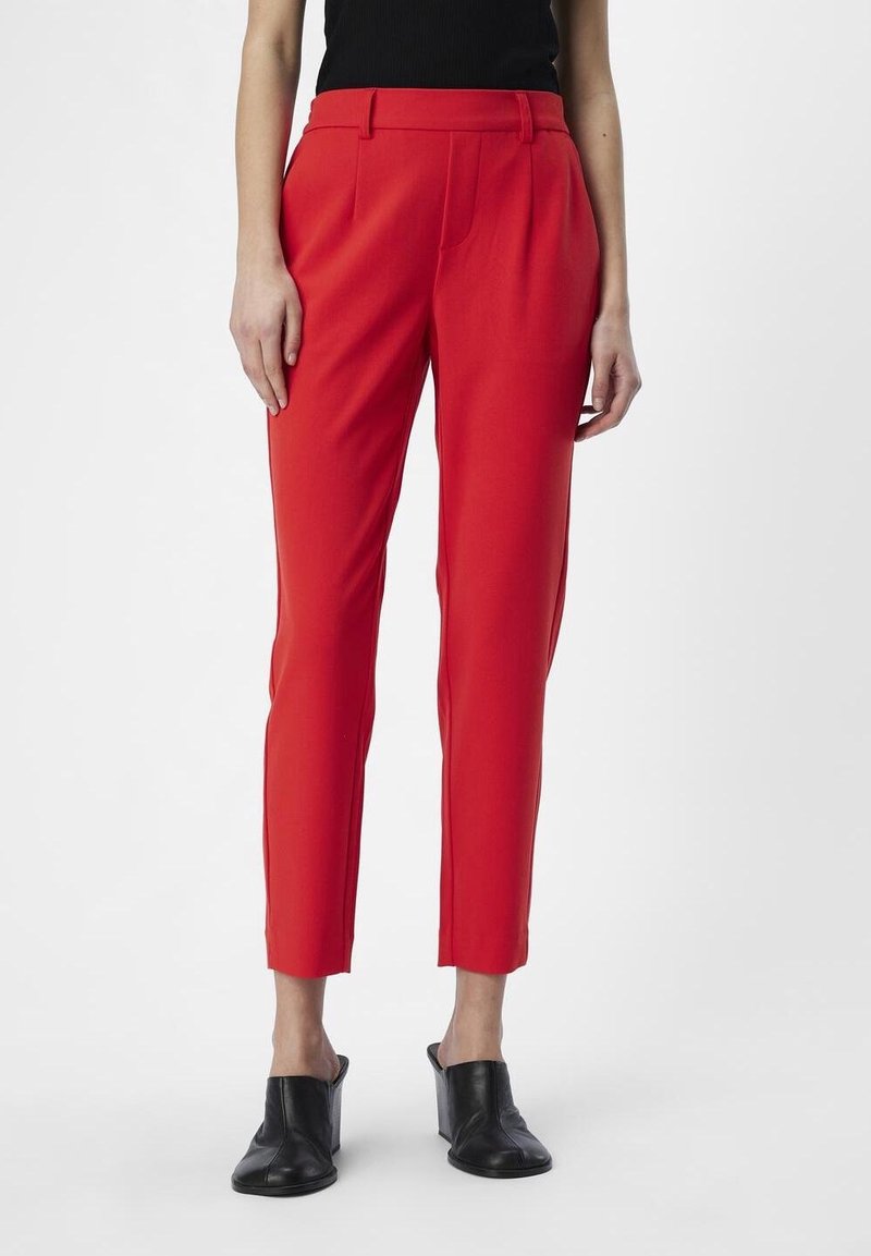 Red tailored trousers with a slim fit, featuring a flat front, belt loops, and side pockets, paired with black open-toed shoes.