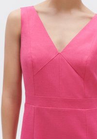 Roze jurk met een V-hals, gestructureerde lijfje met naad-oversteken en een aansluitende taille. Gemaakt van een geweven stof met textuur.