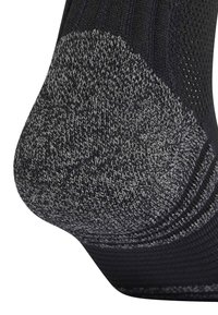 Calcetín negro con talón gris que presenta un punto de textura. Tejido suave en la parte superior con un patrón de malla transpirable cerca del puño.