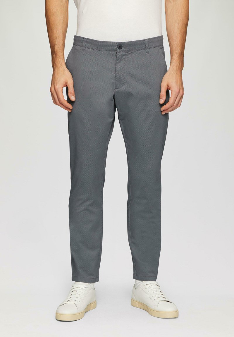 Grijze taps toelopende broek in een rekbare katoenmix; heeft een platte voorkant, zijzakken en een knoopsluiting. G gedragen met witte sneakers.