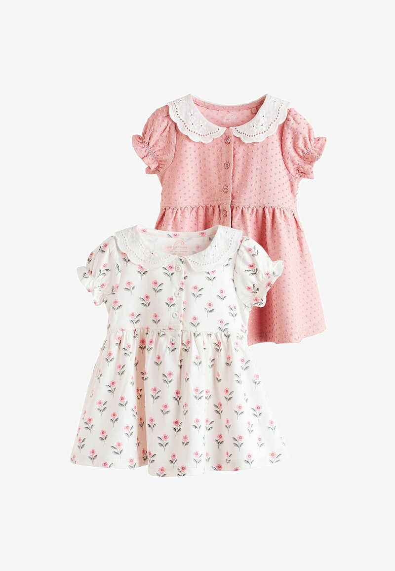 Two baby dresses, one pink with textured dots and white scalloped collar, one white with pink floral pattern and matching collar, both short-sleeved.